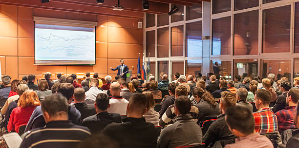 Speaker giving a talk in conference hall at business event. Audience at the conference hall. Business and Entrepreneurship concept.